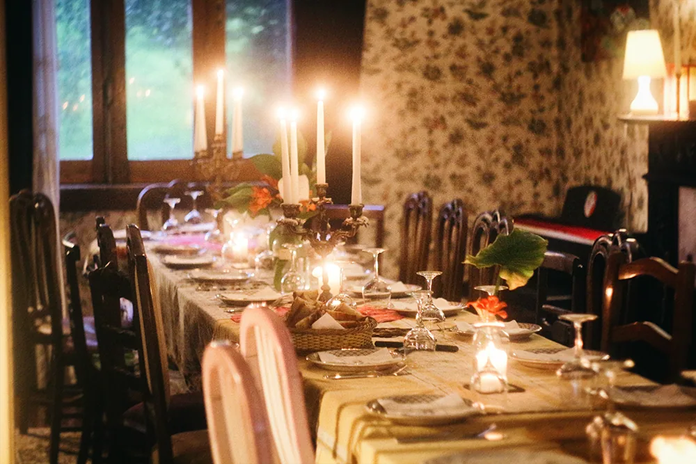Mesa longa iluminada por velas com convidados a conversar