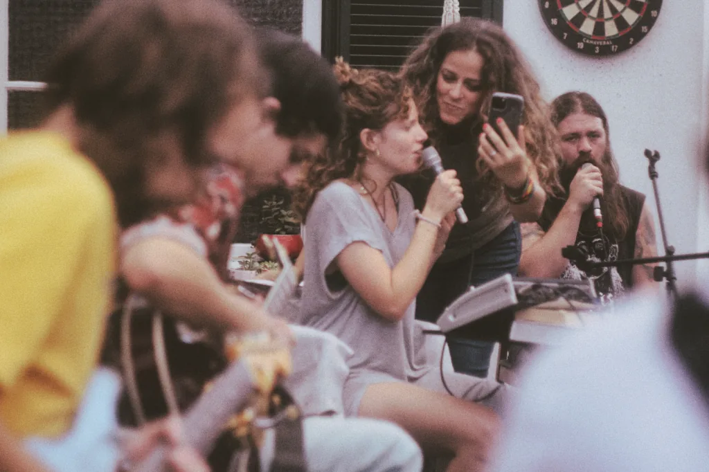 Sessão de música ao vivo num pátio interior, com pessoas a cantar e a partilhar